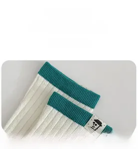 Close-up of white and green ribbed crew socks featuring a minimalist cartoon face tag