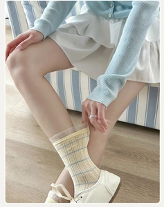 Close-up of light yellow striped socks with lace mesh trim on a wooden floor