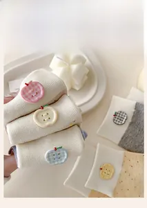 Close-up of knit socks with colorful apple-shaped buttons and macaron speckled yarn texture