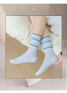 Detail view of light blue striped crew socks with grey ruffled edges and high elasticity