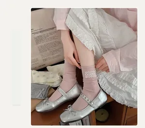 Dettaglio calzini rosa a coste con bordo in pizzo bianco e scarpe Mary Jane argento