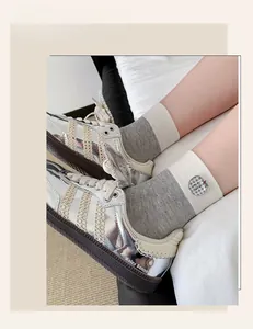 Close-up of metallic silver mirror sneakers with beige knit stripes and crew socks