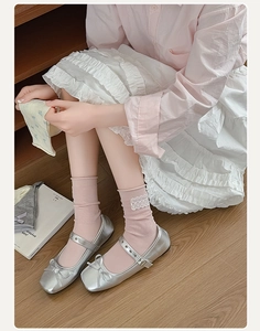 Dettaglio calzini rosa con fiori in pizzo e ballerine argentate in stile balletto