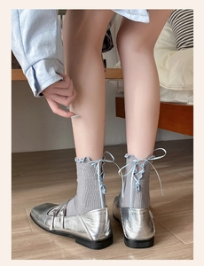 Detail of gray knit socks with light blue ribbon lace-up bows and ruffled edges
