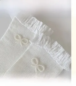 Detail of white cotton lace socks with sweet pearl bow and elegant ruffle cuff