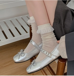 Dettaglio scarpe Mary Jane argento con fiocchi e calze con bordo in pizzo sul modello