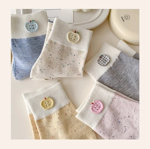 Close-up of pastel cotton blend mid-calf socks featuring apple buttons and speckled yarn
