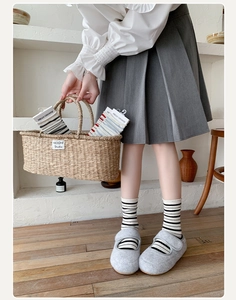 Detail of colorful striped cotton crew socks with rolled edges paired with felt flat shoes