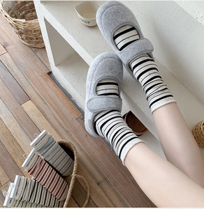 Detail shot of colorful striped cotton socks with rolled cuffs and casual felt slippers