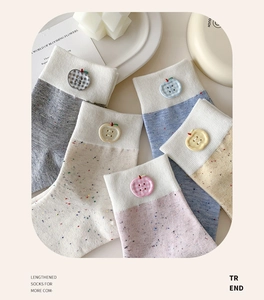 Detail of speckled yarn socks featuring unique apple buttons and ribbed cuff textures