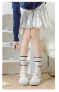 Close-up of white cotton crew socks featuring three layers of brown ruffled lace cuffs