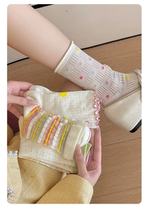 Close-up of sheer mesh socks with colorful polka dots and stylish wavy ruffled edges