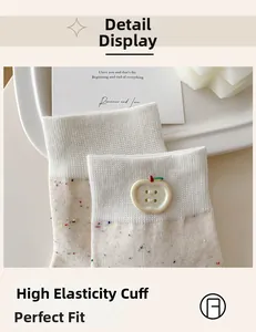 Detail of white knit sock with colorful specks and a cute red apple decorative button
