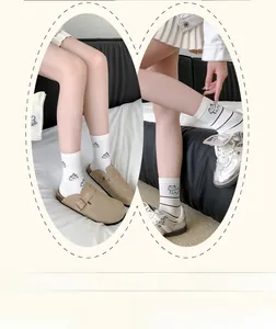 Detailed view of white calf socks with black stripes and cute cartoon embroidery