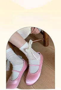 Detail of white cotton lace socks with pink ribbon bows and satin Mary Jane shoes