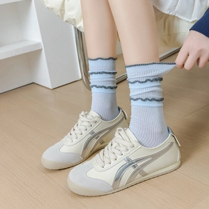 Breathable light blue ruffle trim crew socks paired with casual beige sneakers on wood
