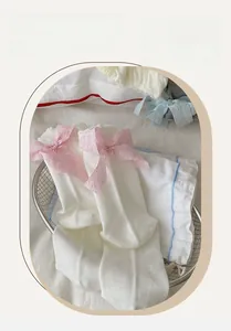 Close-up of mesh knit socks with pink ruffled bows in a decorative metal basket