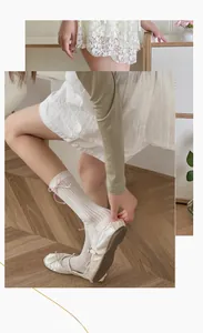 Détail de chaussettes en résille blanches avec nœuds roses et texture ajourée