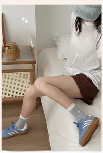 Detail of grey crew socks with heart embroidery and white ribbed cuffs in a cozy setting