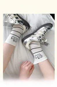 Detail of white cotton crew socks featuring black stripes and a cute bear embroidery