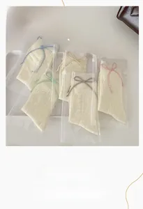 Détail de chaussettes en tricot crème avec nœuds en cuir colorés dans des sacs zippés