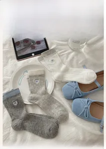 Detailed view of summer mid-calf socks with heart bow embroidery on white bedding