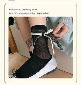 Detail of black lace bow and white ribbon on ribbed ballet style sheer crew socks
