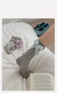 Detailed view of grey mesh socks featuring large decorative bows in a sweet Lolita style