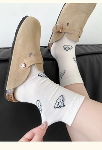 Detail of white cotton sock with cute cartoon dog embroidery and breathable knit texture