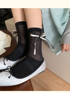 Detail of balletcore black calf socks with white satin bows and delicate lace trim