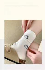 Close-up of white mid-calf socks with blue cartoon clouds and rib knit details