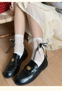 Detail of white striped socks with side lace bow paired with black leather loafers