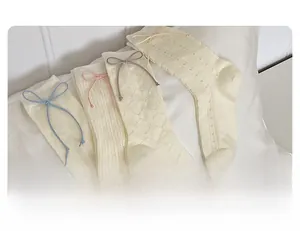 Détail de quatre paires de chaussettes en maille crème avec nœuds et motifs tricotés