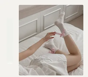 Detail of white mesh socks with ruffled trim and pink lace bow on the back heel