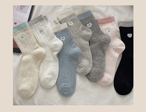 Flat lay of cotton knit crew socks featuring heart bow embroidery and ribbed contrast cuffs