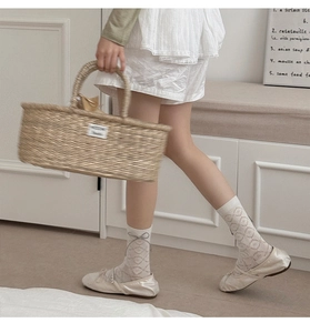 Détail de chaussettes blanches en résille à nœuds en cuir avec ballerines et panier en paille