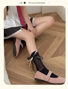 Detail of sheer black ballet socks with lace trim and bow ribbons worn with Mary Jane shoes