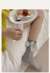 Detail of grey mesh knit lolita socks featuring large blue bows and ruffle trim