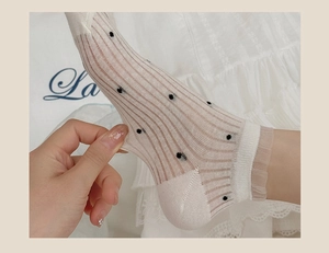 Close-up of sheer white mesh socks with black polka dots and delicate lace trim cuff