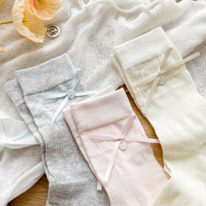 Detail of three pairs of knit lace socks with silk ribbons and decorative buttons