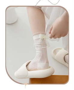 Détail de chaussettes mi-mollet en dentelle blanc crème avec nœud et maille filet