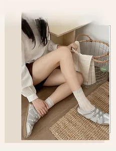 Close-up of light grey mesh socks with white bow detail paired with silver ballet flats
