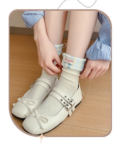 Close-up of white Mary Jane shoes with double straps and blue gingham cuff socks