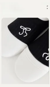 Close-up of seamless toe and bow embroidery on black and white cotton crew socks