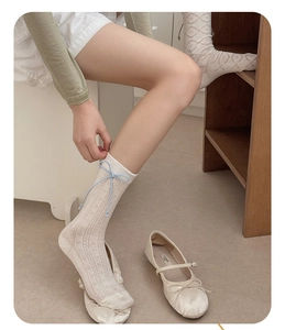 Gros plan de chaussettes blanches ajourées avec un petit nœud en cuir bleu clair
