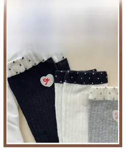 Close-up of ribbed knit socks with heart embroidery and bow details in three colors