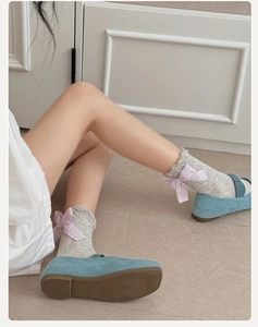 Detail of light gray mesh socks with pink lace bow paired with blue suede flats