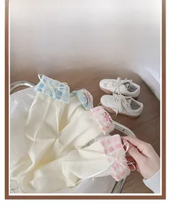 Detail of sweet ballet style mid-tube socks with ribbon bows and plaid folded cuffs
