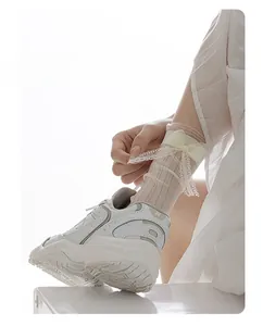 Détail de chaussettes en dentelle blanc crème avec nœuds en satin et maille résille