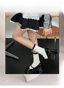 Detail of white crew socks with black polka dot trim and delicate floral embroidery
